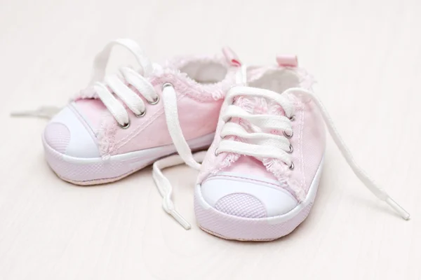 Little girlie baby shoes on a wooden floor — Stock Photo, Image