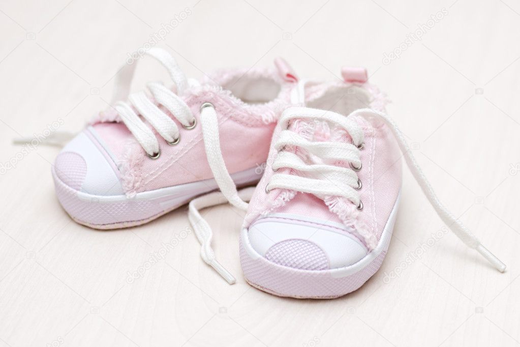 Little girlie baby shoes on a wooden floor
