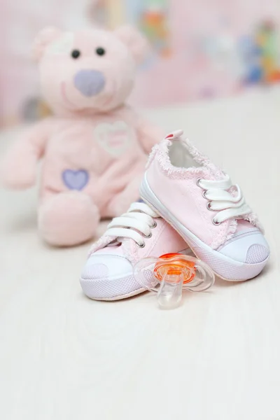 Baby shoes and teddy bear toy on a wooden floor — Stock Photo, Image