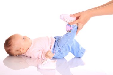 Mother putting shoes on baby clipart