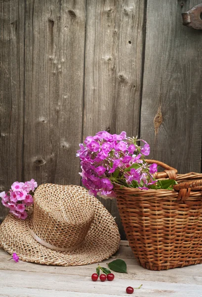 Basket of flowers and a straw hat — Stock Photo, Image