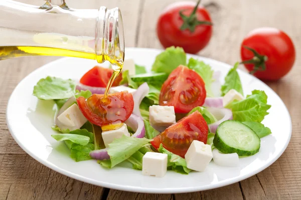 Oil pouring over fresh salad — Stock Photo, Image