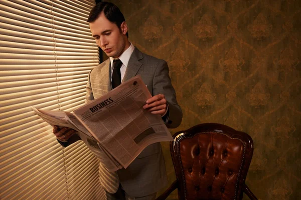 Человек в костюме читает газету — стоковое фото