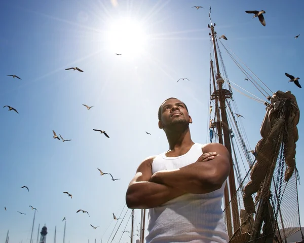 Knappe Afro-Amerikaanse man tegen boot de mast. — Stockfoto