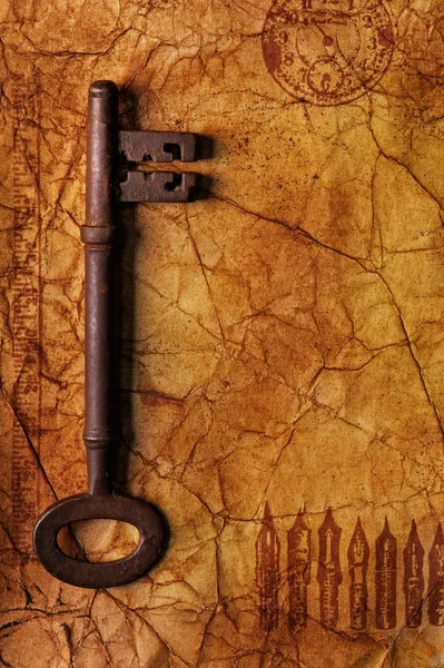 Старый ключ на текстурированной бумаге — стоковое фото