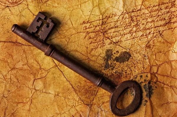 The old key on the textured paper — Stock Photo, Image