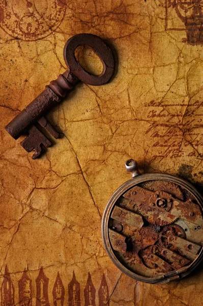 Den gamla nyckeln med ett kugghjul på texturerat papper — Stockfoto