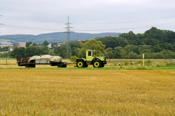 stock image The tractor with the trailer goes across the field