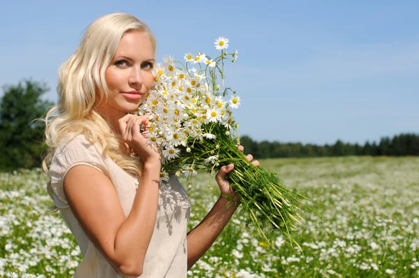 Beautiful woman at the meadow with bunch of chamomiles. — Stock Photo, Image