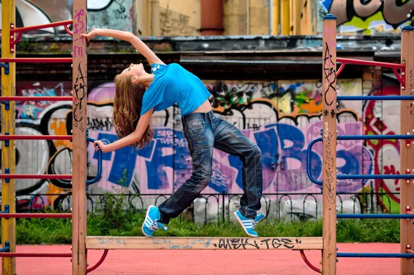 Mooi meisje op de straat met graffiti muur. — Stockfoto