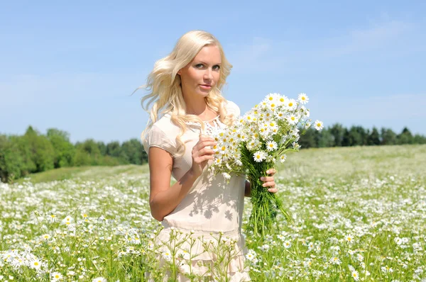 Beautiful young woman at the meadow with bunch of chamomiles. — Stock Photo, Image