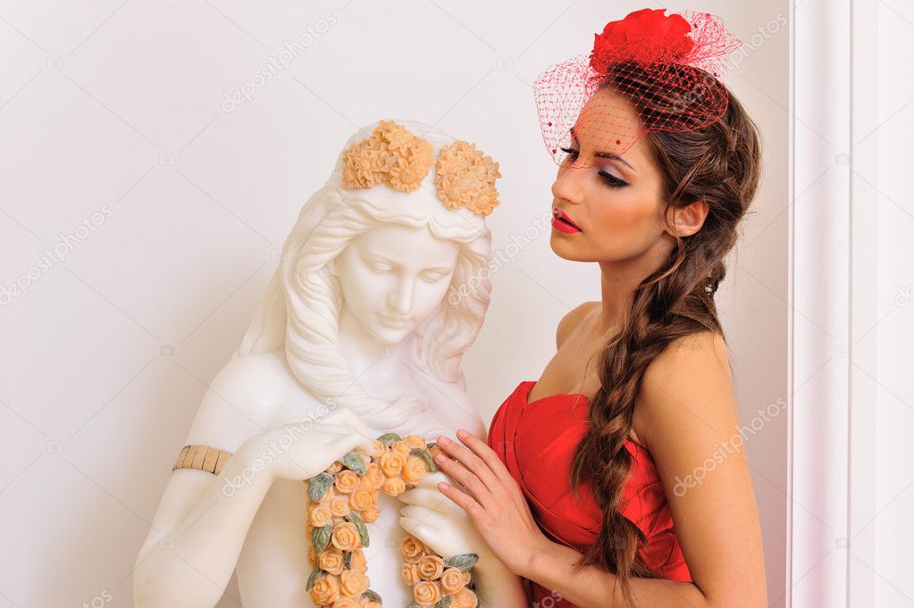 Beautiful woman in red with antique statue