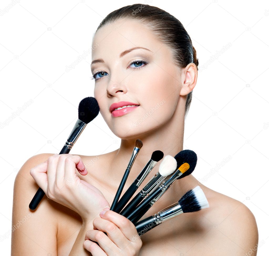 Beautiful young woman holding makeup brushes — Stock Photo