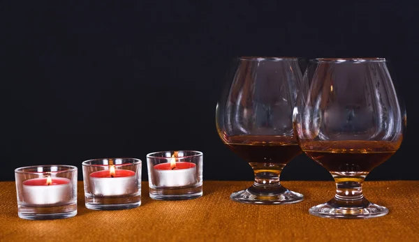 Two glasses of brandy and lit candles — Stock Photo, Image