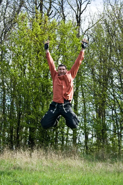 Happy man on meadow jumping in the air — Stock Photo, Image