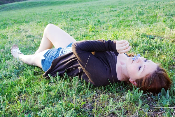 Счастливая молодая женщина лежит на зеленой траве — стоковое фото