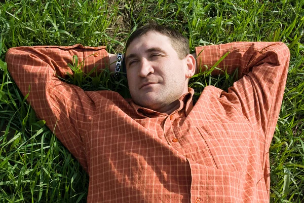 Ung man liggande på gräset — Stockfoto