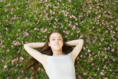 Genç kadın çimlerin üzerinde yatıyor.