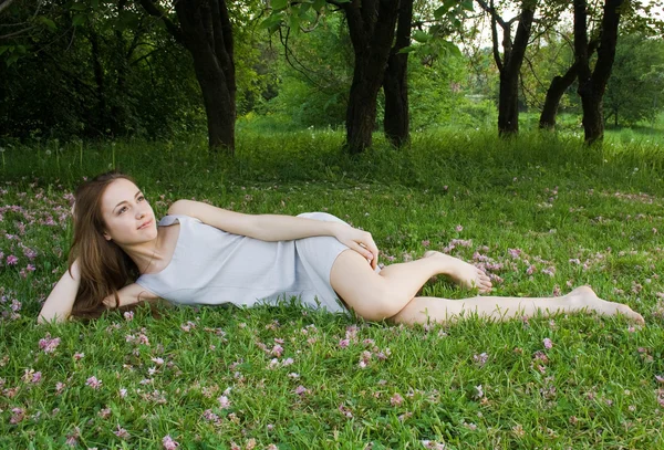 Young cute girl is leaning on the green gras — Stock Photo, Image