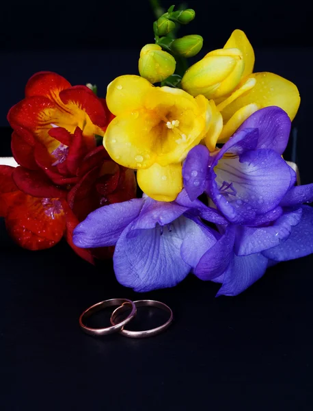 Wedding rings and a bouquet of freesias — Stock Photo, Image