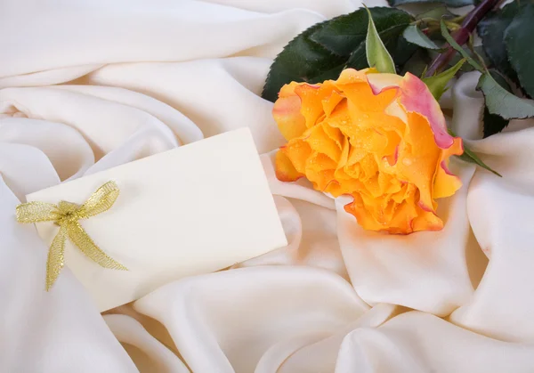 Rosa amarela e um cartão em uma seda doce — Fotografia de Stock