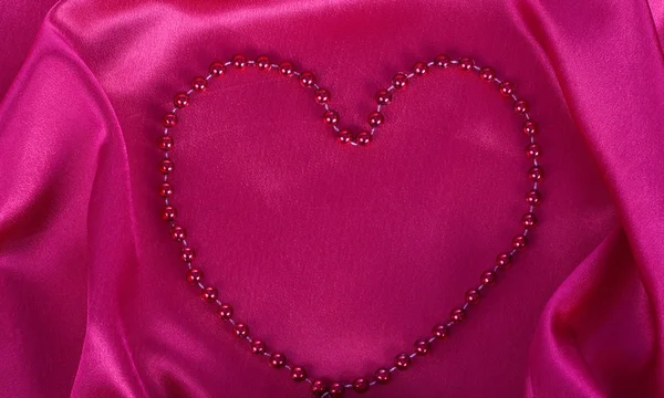 Heart of the ornaments on red silk — Stock Photo, Image