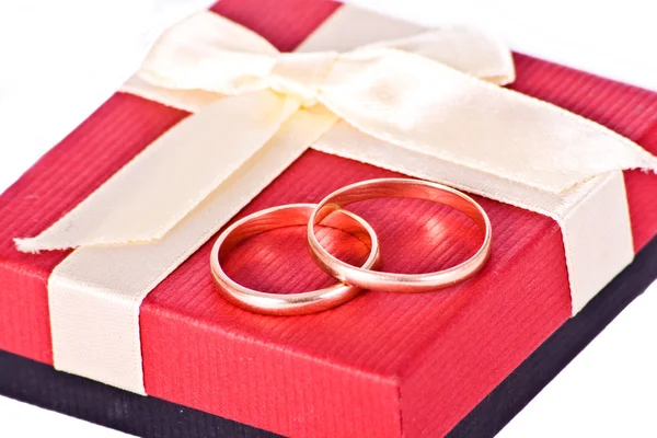 Золотые обручальные кольца рядом с красной коробкой — стоковое фото