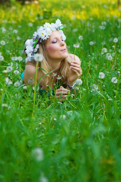 Young woman blowing a dandelion on fields — Stock Photo, Image