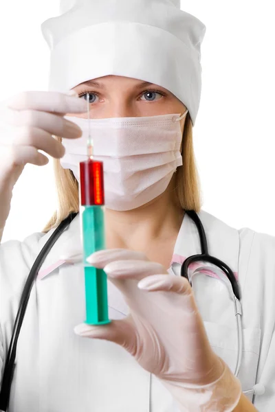 Vrouwelijke arts in een masker en een injectiespuit in handen — Stockfoto