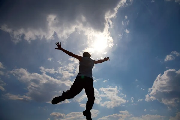 Young man jumping against cloudy sky — Stock Photo, Image