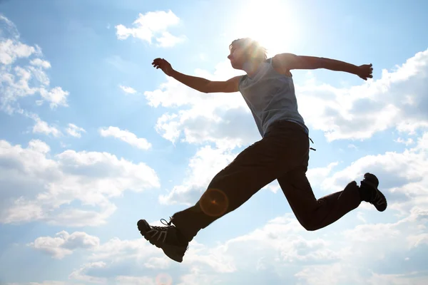 Молодий чоловік стрибає проти хмарного неба — стокове фото