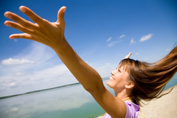 Gyönyörű fiatal nő kinyitotta a kezét örömmel a kék ég — Stock Fotó