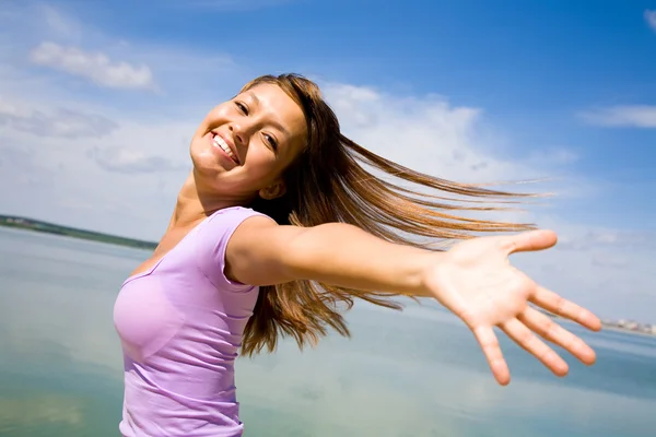 Mooie jonge vrouw opende haar handen met vreugde aan de blauwe lucht — Stockfoto