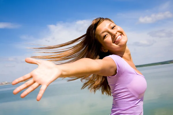Mooie jonge vrouw opende haar handen met vreugde aan de blauwe lucht — Stockfoto