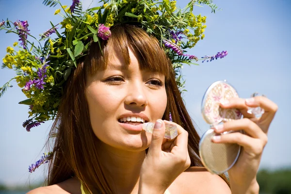 Portret młodej kobiety piękne w wieniec kwiatowy używa szminka — Zdjęcie stockowe
