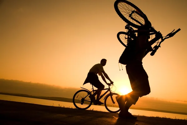 Člověk nese kolo při západu slunce — Stock fotografie