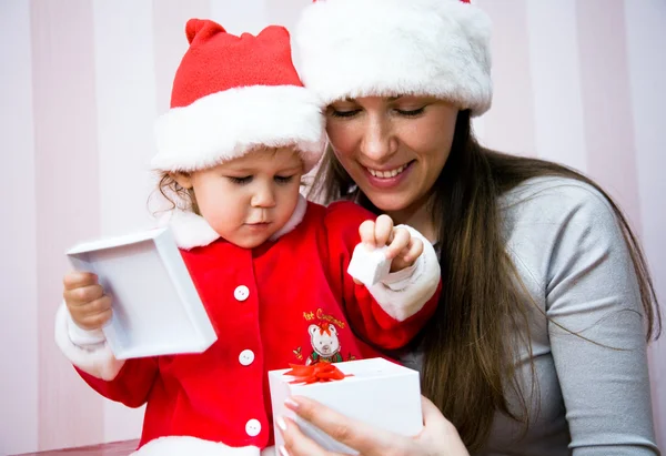 Mooie moeder met een klein kind open een gift van Kerstmis — Stockfoto