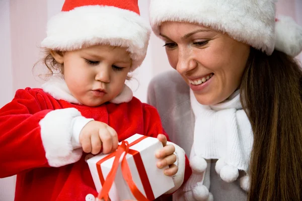 Hermosa madre con un niño pequeño abrir un regalo de Navidad —  Fotos de Stock