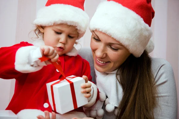 Hermosa madre con un niño pequeño abrir un regalo de Navidad — Foto de Stock