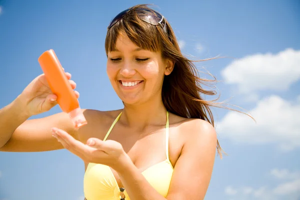 Mujer en bikini untar crema protectora —  Fotos de Stock