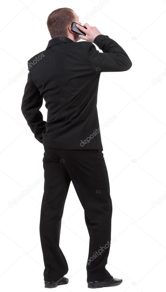 Rear view of business man in black suit talking on mobile phone