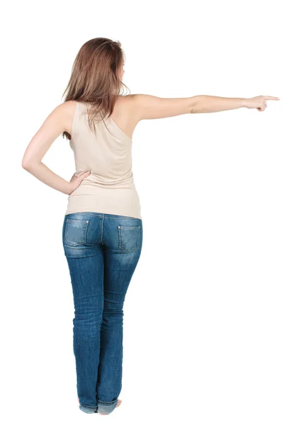Vacker ung kvinna som pekar på väggen. bakifrån. — Stockfoto