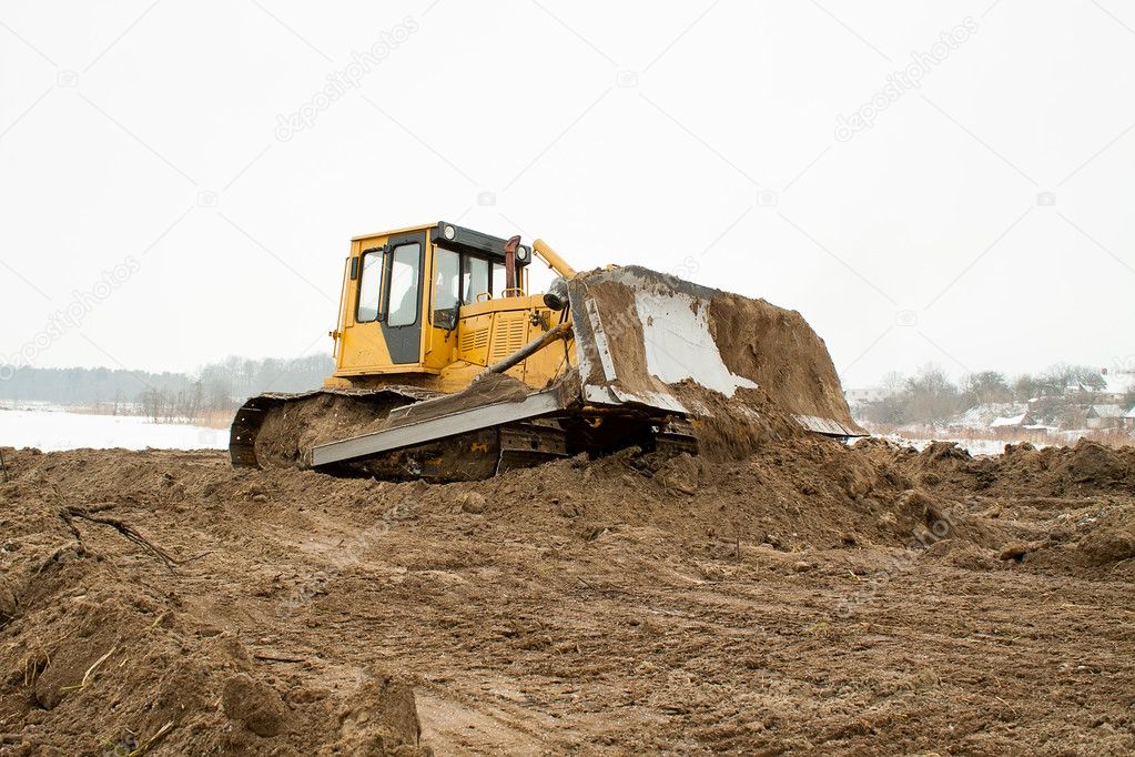A yellow bulldozer working in the winter