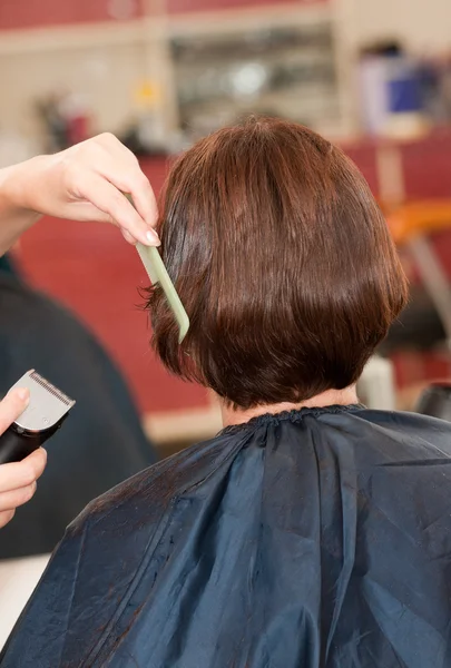 Hands of the hairdresser doing a hairdress to the girl by means — Stock Photo, Image