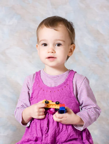 A criança em um vestido rosa com brinquedos — Fotografia de Stock