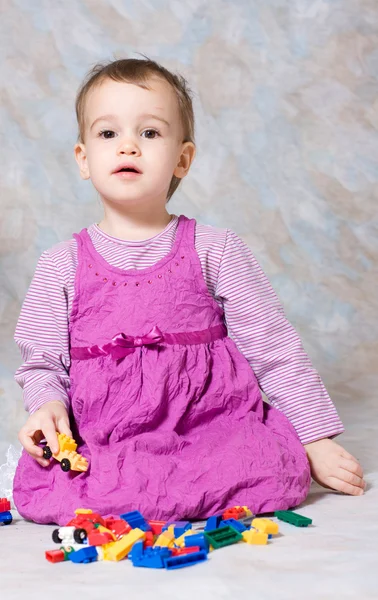 Ребенок в розовом платье с игрушками — стоковое фото