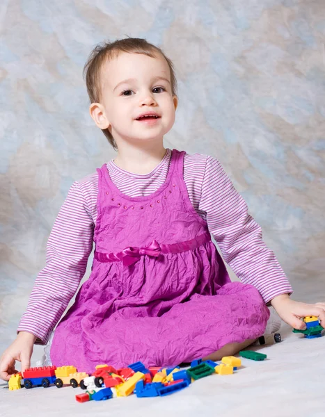 Das Kind im rosa Kleid mit Spielzeug — Stockfoto