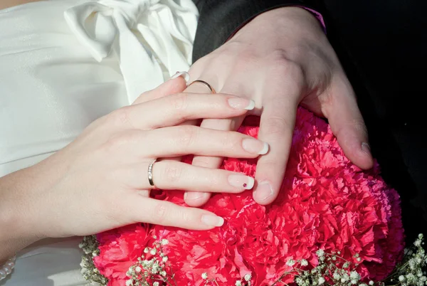 Hands of a newly-married couple with rings on a bouquet — Stock Photo, Image