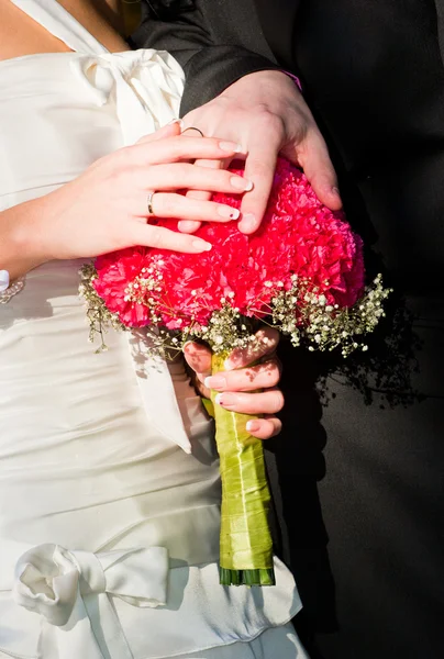 Mãos de um casal recém-casado com anéis em um buquê — Fotografia de Stock