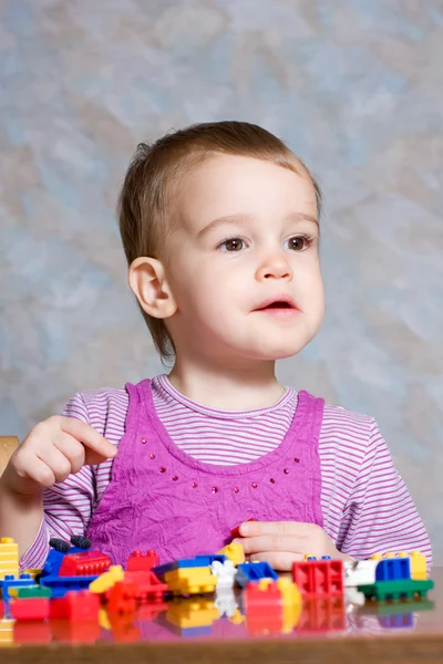 Het kind in een roze jurk met speelgoed — Stockfoto